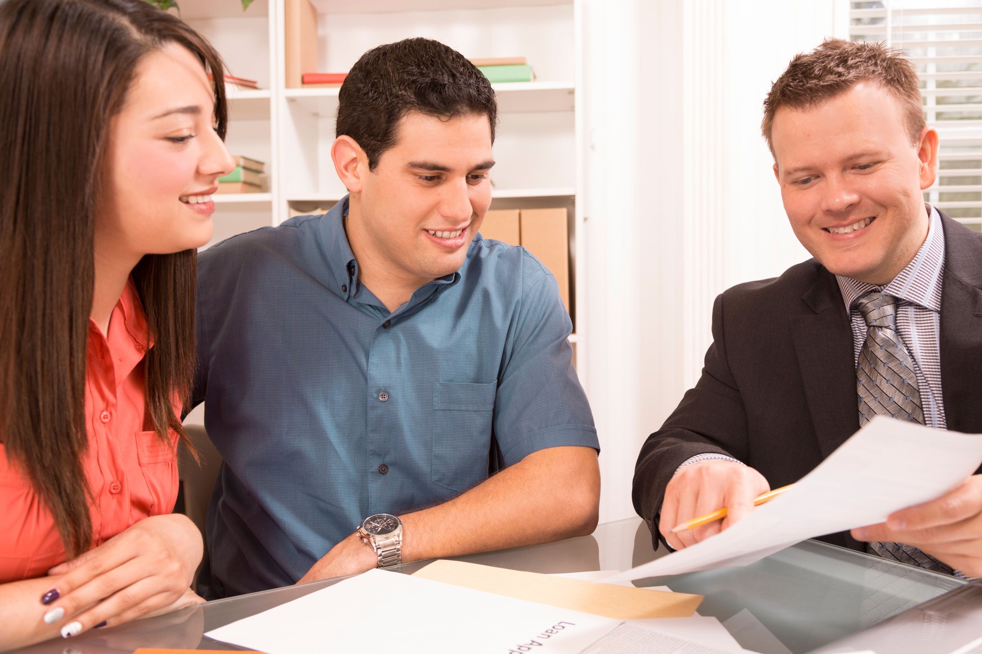 Business: Latin couple reviews financial documents with advisor.